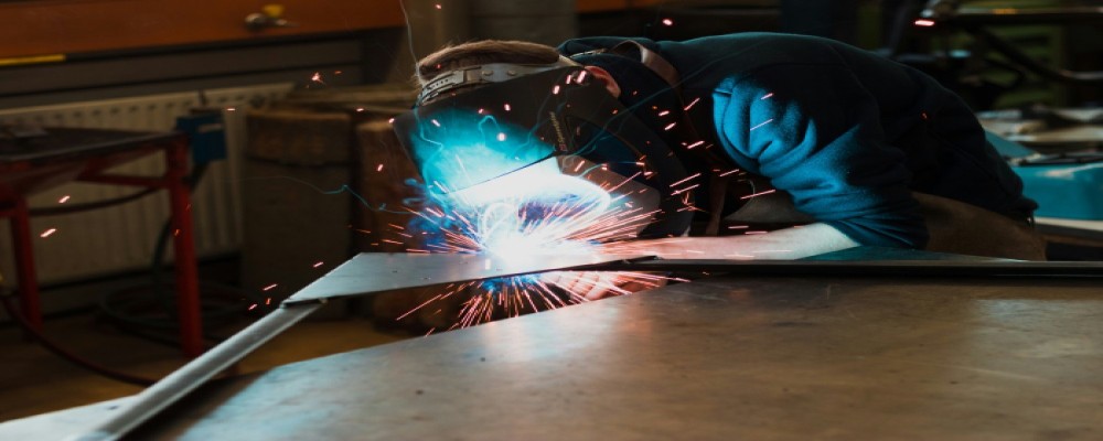 Welder working in an engineering workshop using professional industrial tools and PPE