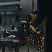 Worker using an angle grinder on metal in an engineering workshop, producing sparks.
