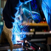 Industrial operator welding metal with PPE, illustrating why reliability and total cost of ownership matter more than unit price in industrial purchasing decisions